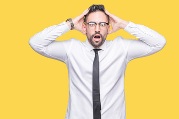 Young handsome business man wearing glasses over isolated background Crazy and scared with hands on head, afraid and surprised of shock with open mouth