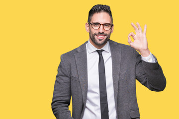 Young handsome business man over isolated background smiling positive doing ok sign with hand and fingers. Successful expression.