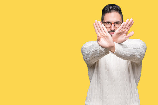 Young handsome man wearing glasses over isolated background Rejection expression crossing arms and palms doing negative sign, angry face