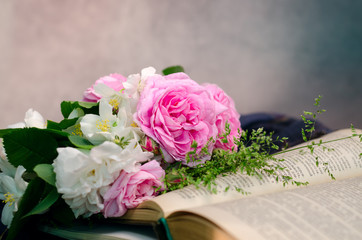Gentle pink roses bouquet with old books on a old wooden background.