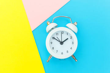 Ringing twin bell classic alarm clock isolated on blue yellow pink pastel colorful geometric...