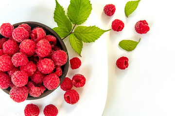 Fresh organic raspberries in a clay plate on white background.