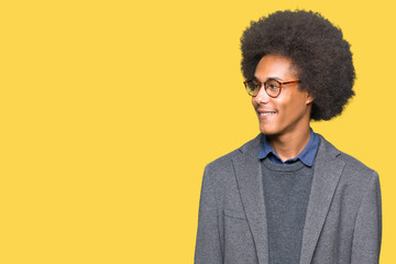 Young african american business man with afro hair wearing glasses looking away to side with smile on face, natural expression. Laughing confident.
