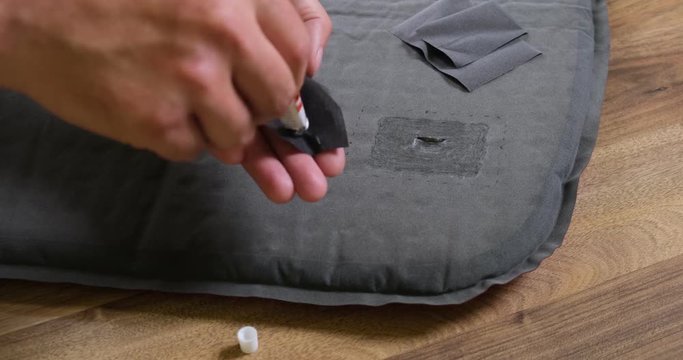 Repairing punctured sleeping pad for camping - fast forward, time lapse. Full procedure: applying glue on patch from repair kit, positioning patch, pressing down on patch. 4K DCI, 200 Mbps.