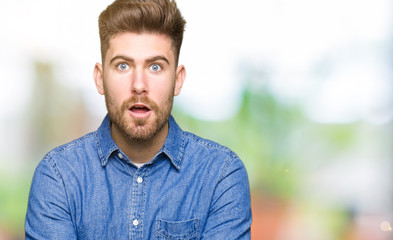 Young handsome blond man wearing casual denim shirt afraid and shocked with surprise expression, fear and excited face.