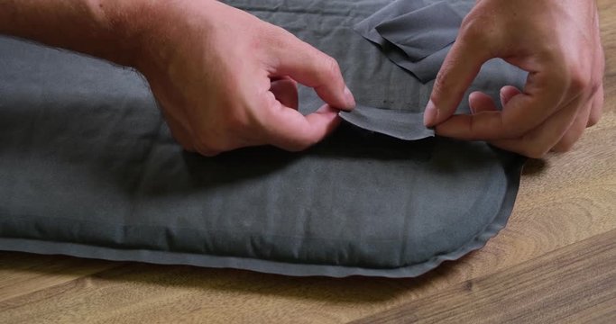 Close up of male hand applying a repair patch on a mattress/sleeping mat and pressing on it. Home made repair of a camping pad.