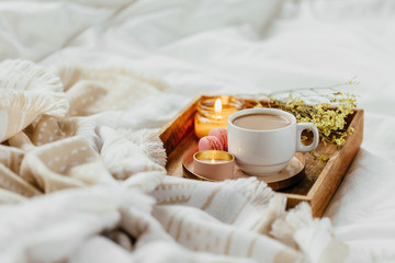 Tray of coffee and candles with warm plaid on white bedding . Breakfast in bed.  Scandinavian style.  Flat lay, top view
