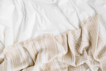 Fototapeta na wymiar White bedding with warm plaid. Cozy background with copy space. Scandinavian style. Flat lay, top view