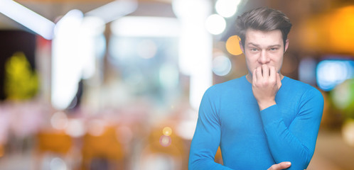 Young handsome man wearing blue sweater over isolated background looking stressed and nervous with...
