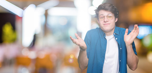Young handsome man wearing glasses over isolated background clueless and confused expression with...