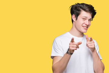 Young handsome man wearing casual white t-shirt over isolated background pointing fingers to camera with happy and funny face. Good energy and vibes.