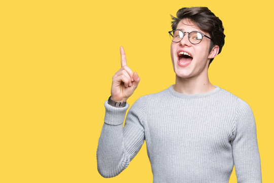 Young handsome man wearing glasses over isolated background pointing finger up with successful idea. Exited and happy. Number one.