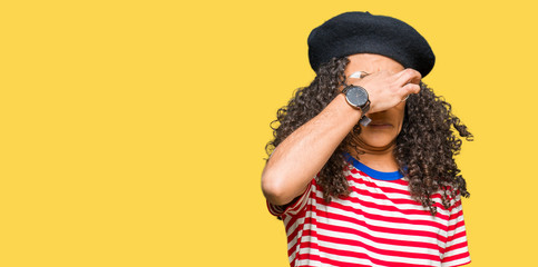 Young beautiful woman with curly hair wearing glasses and fashion beret smelling something stinky...