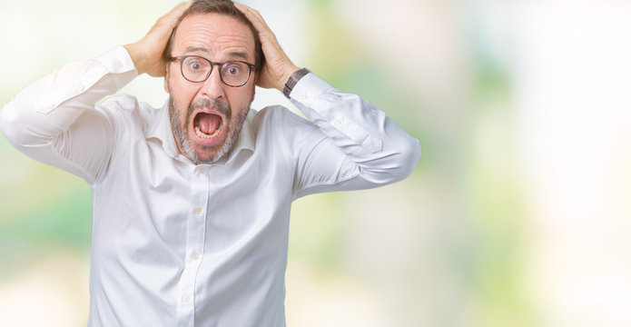 Handsome middle age elegant senior business man wearing glasses over isolated background Crazy and scared with hands on head, afraid and surprised of shock with open mouth