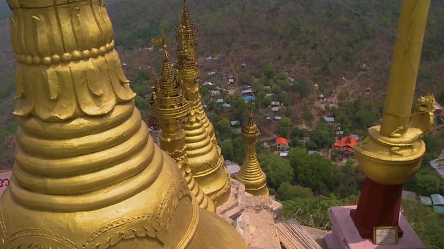 A high angle shot of golden stupas in a temple built close to each other and descending down a hill