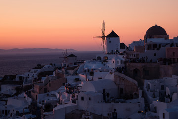The white village of Oia, on the island of Santorini, Greece during a romantic orange sunset in the evening.