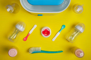 Pacifier and baby feeding accessories on yellow background