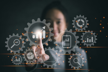 Business data analytics process management with a consultant touching connected gear cogs with KPI financial charts and graph, automated marketing dashboard