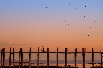 Unidentified people walk on U Bein bridge at sunset in Myanmar.
