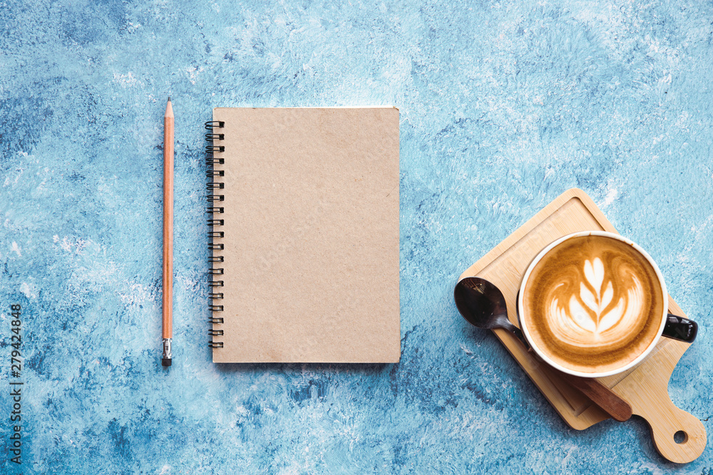 Poster empty notebook with cup of coffee latte on blue abstract background.