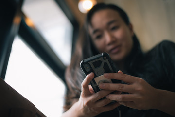 Happy smiling Asian woman holds mobile phone, close up focus on female hands and device. Customer buying goods via internet, friends chatting online, generation addicted with gadgets concept