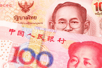 A red one hundred Thai baht along with a red one hundred yuan note from the People's Republic of China, close up in macro
