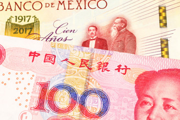 A one hundred Mexican peso bill, shot in macro with a red one hundred yuan bank note from the People's Republic of China