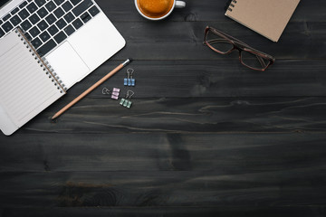 Modern dark wood office desk table with laptop, smartphone and other supplies with cup of coffee. coppy space for input the text in the middle. Top view, flat lay.