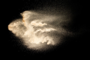 Abstract sand cloud.Golden colored sand splash agianst dark background.Yellow sand fly wave in the...