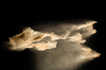 Plakat Abstract sand cloud.Golden colored sand splash agianst dark background.Yellow sand fly wave in the air. Sand explode on black background ,throwing freeze stop motion concept.