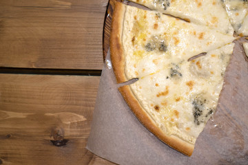 Four cheese pizza quattro fromaggi on a rustic dark colored wooden board background, close up