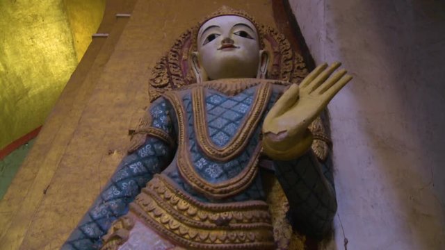 A low angle shot of a painted statue of buddha inside a temple in Burma