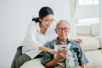 Elderly man using a phone with his daughter