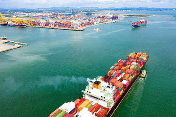 top aerial view of the large TEU containers ships arrival and departure the port, carriage the shipment from loading port to destination discharging port, transport and logistics services to worldwide