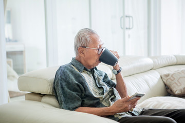 Senior man drinking hot tea on the couch