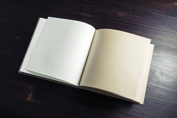Fototapeta premium Blank book or brochure on dark wooden background. Copy space for text.