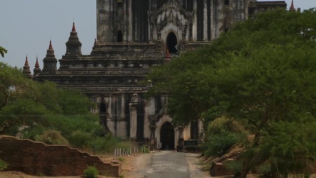 A low angle shot of the topmost part of the faded white walls of an ancient temple with a golden stupa on top