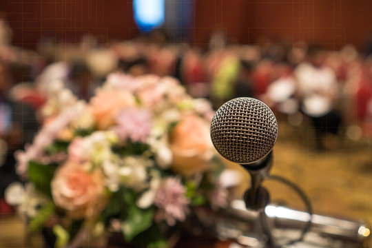 Seminar Conference Concept : Close-up Microphones on abstract blurred of speech in conference meeting room, front flowers speaking blur bokeh light in event convention hall in hotel background