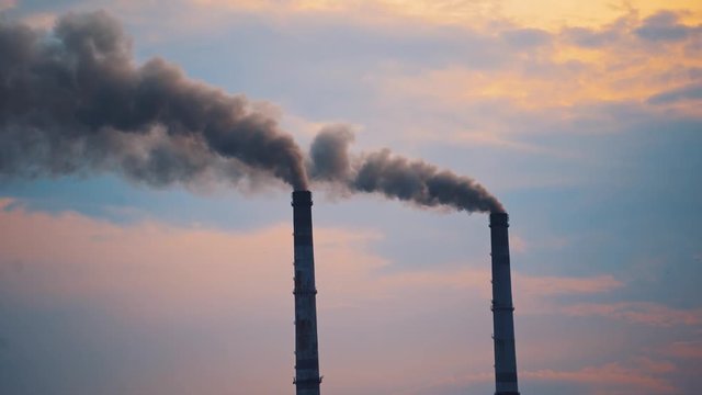 Air pollution by smoke coming out of two factory chimneys. Smoking pipes against the sky. Ecological disaster, air pollution. Environmental problems badly affecting life.