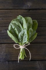 bunch of fresh spinach leaves on a wooden table. Vertical orientation. Healthy tasty vegan food.