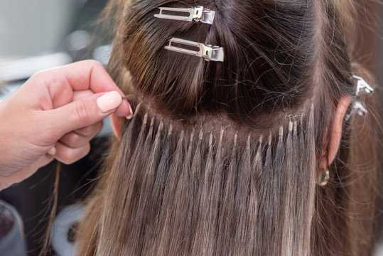 Professional process of hair extension for a woman with the help of artificial, in a beauty salon close up