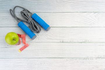 Top or flat lay view of apple fruit and skipping rope with copy space area on wooden background. Healthy concept. Selective focus.