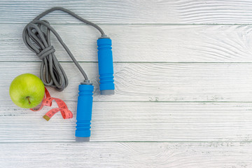 Top or flat lay view of apple fruit and skipping rope with copy space area on wooden background. Healthy concept. Selective focus.