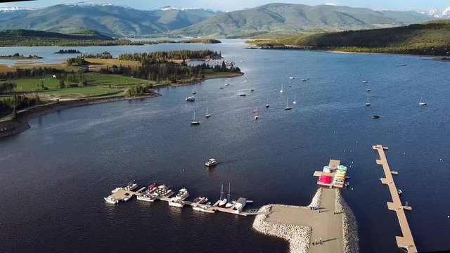 Aerial, rising, drone shot, overlooking the Frisco marina, sailboats, on Lake Dillon Reservoir and mountains in the background, on a sunny, summer evening, in Frisco, Summit County, Colorado, USA
