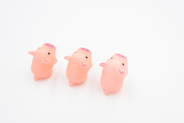 Three cute pink toy piglets neatly arranged standing on a white background