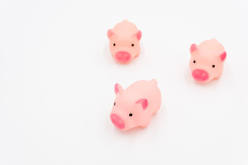 Three cute pink toy pigs are running forward on a white background