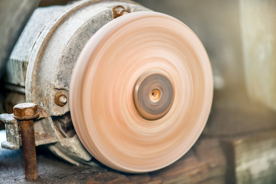A machine for turning a round shape with light. Grinder. Old and rusty grinding whetstone tool. Workplace worker.