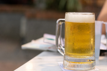 Close up of the cold glass beer with froth in pub & restaurant background.