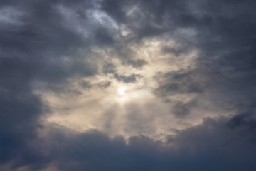 The sky with dark stormy clouds, through which the sun looks_