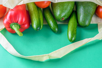 World free of plastic.Reusable eco friendly bamboo grocery shopping bag with vegetables-red pepper, fresh tomatoes cucumber and avocado on green background. Organic products. Less plastic.